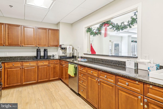 kitchen featuring dishwasher, light hardwood / wood-style flooring, dark stone countertops, and sink