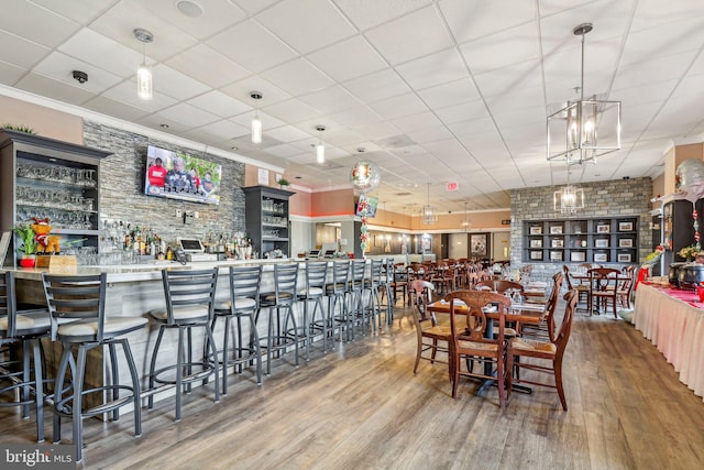 dining space featuring hardwood / wood-style flooring, a drop ceiling, and crown molding