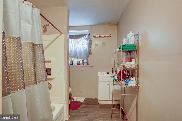 bathroom featuring hardwood / wood-style floors, vanity, and shower / bathtub combination with curtain