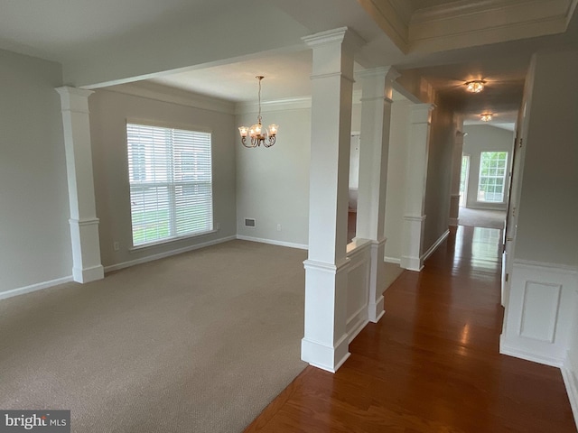 interior space featuring ornate columns, crown molding, a chandelier, and dark carpet