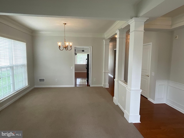 carpeted spare room featuring a chandelier, ornate columns, a wealth of natural light, and ornamental molding