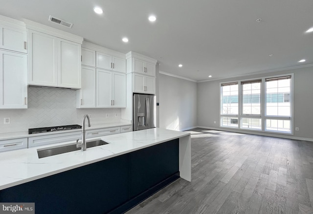 kitchen with stainless steel fridge, light stone counters, white cabinetry, and crown molding