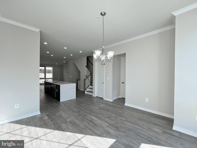 kitchen with pendant lighting, sink, hardwood / wood-style flooring, ornamental molding, and an island with sink