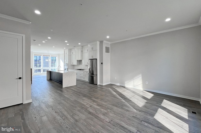 kitchen with stainless steel refrigerator with ice dispenser, a kitchen island with sink, dark wood-type flooring, sink, and white cabinetry