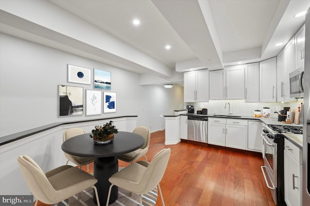 kitchen with white cabinetry, appliances with stainless steel finishes, decorative backsplash, dark hardwood / wood-style floors, and sink