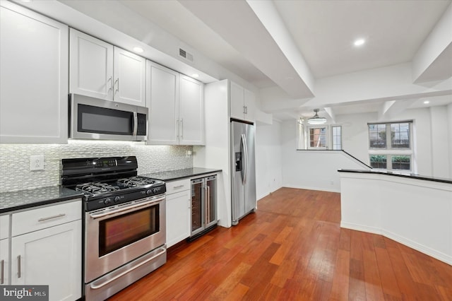 kitchen featuring white cabinets, appliances with stainless steel finishes, light wood-type flooring, and wine cooler