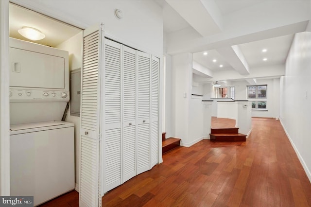 hall with beam ceiling, stacked washer / dryer, and hardwood / wood-style flooring