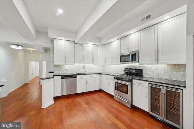 kitchen with wine cooler, sink, white cabinetry, light wood-type flooring, and stainless steel appliances