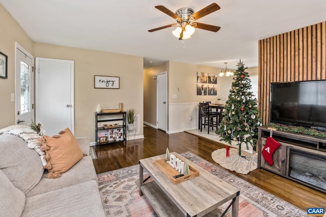 living room featuring ceiling fan with notable chandelier and hardwood / wood-style flooring