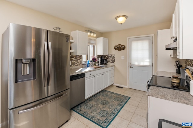 kitchen with decorative backsplash, stainless steel appliances, light tile patterned floors, white cabinetry, and range hood