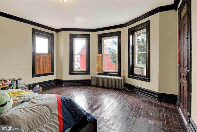 unfurnished bedroom with dark hardwood / wood-style flooring, radiator heating unit, and multiple windows