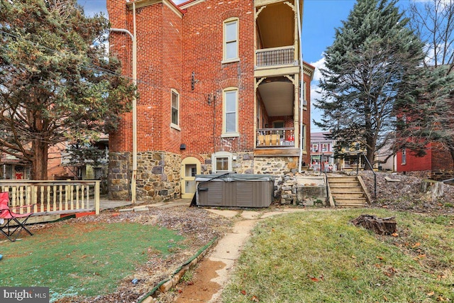 back of house with a yard and a hot tub