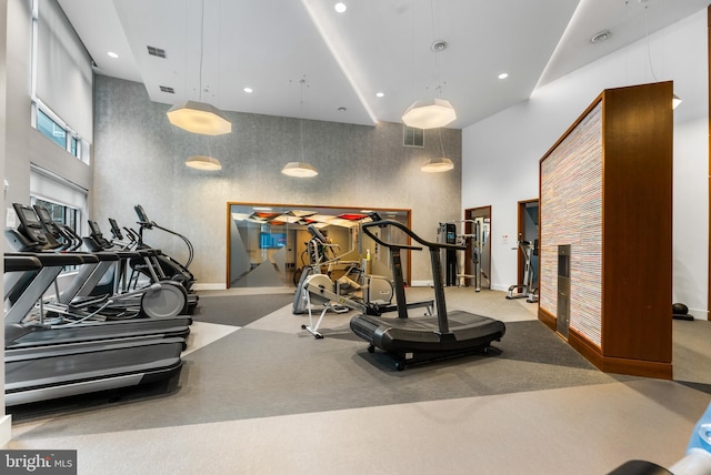 exercise room with visible vents, baseboards, a towering ceiling, and recessed lighting