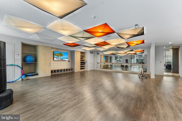 workout area with visible vents, baseboards, and wood finished floors