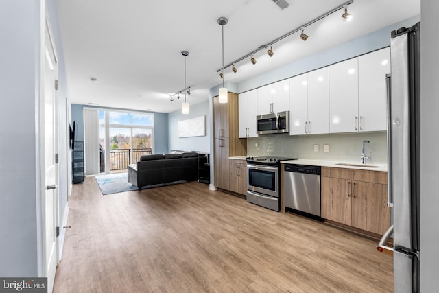 kitchen featuring stainless steel appliances, light countertops, open floor plan, white cabinets, and modern cabinets