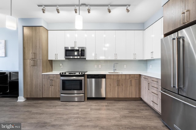 kitchen featuring decorative light fixtures, stainless steel appliances, light countertops, white cabinetry, and a sink