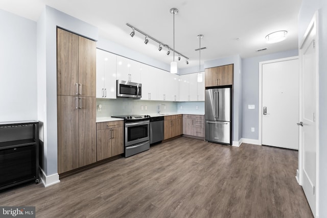 kitchen with brown cabinets, hanging light fixtures, stainless steel appliances, light countertops, and white cabinetry