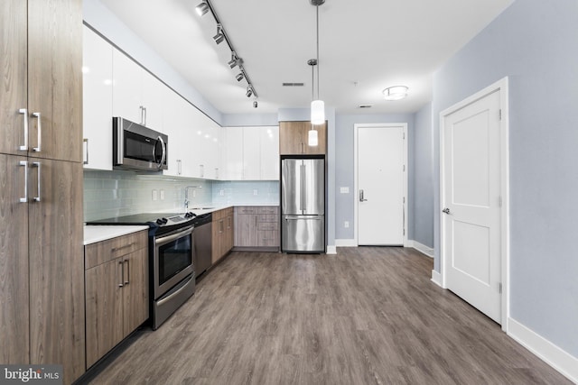 kitchen with decorative backsplash, white cabinets, appliances with stainless steel finishes, light countertops, and pendant lighting