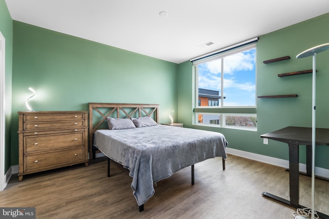 bedroom featuring wood finished floors, visible vents, and baseboards