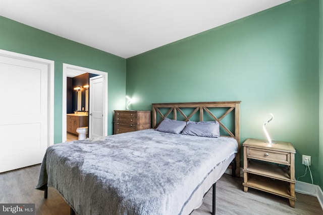 bedroom featuring ensuite bathroom and wood finished floors