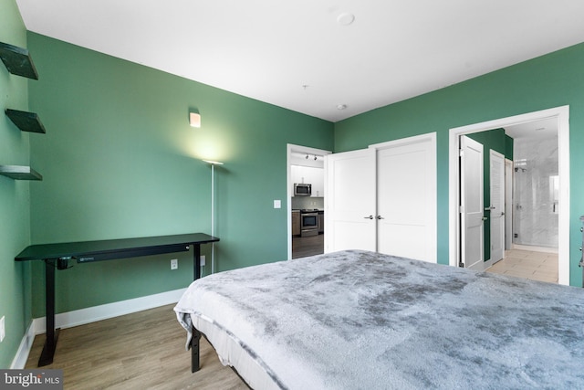 bedroom featuring ensuite bath, light wood-style flooring, and baseboards