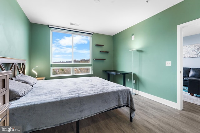 bedroom featuring visible vents, baseboards, and wood finished floors