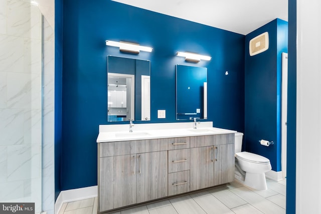 full bath featuring baseboards, a sink, toilet, and double vanity