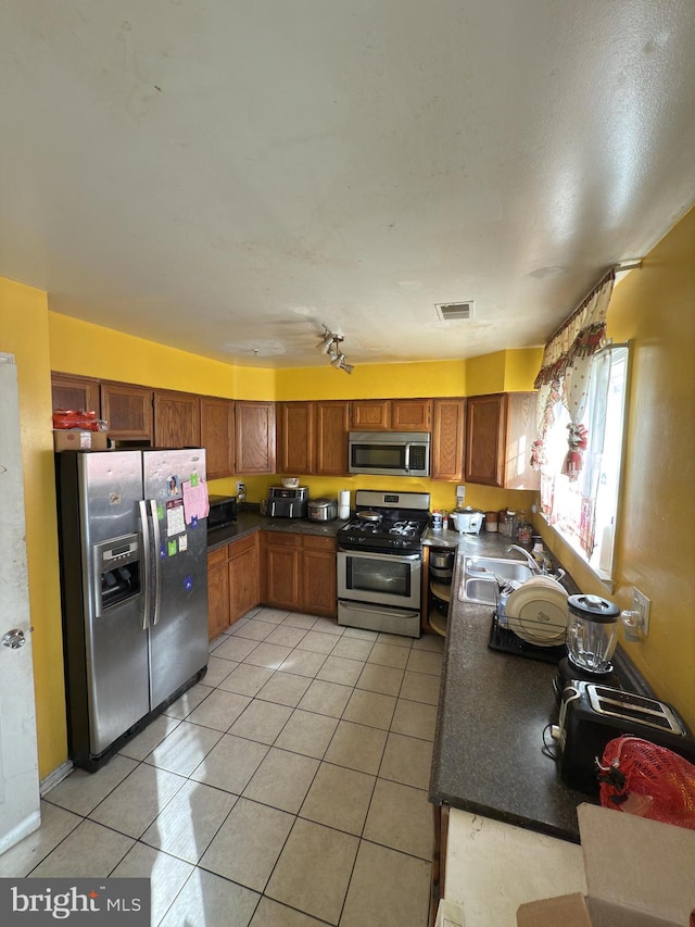 kitchen with sink, light tile patterned floors, and stainless steel appliances