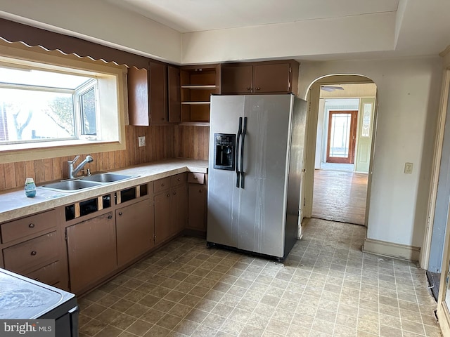 kitchen with wood walls, sink, stove, and stainless steel refrigerator with ice dispenser