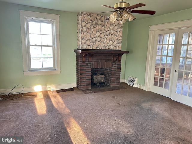 unfurnished living room featuring carpet flooring, ceiling fan, a fireplace, and french doors