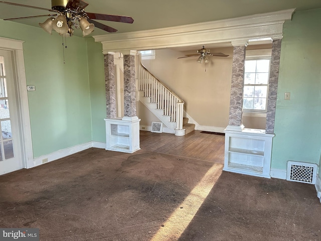 interior space with decorative columns, ceiling fan, and dark carpet