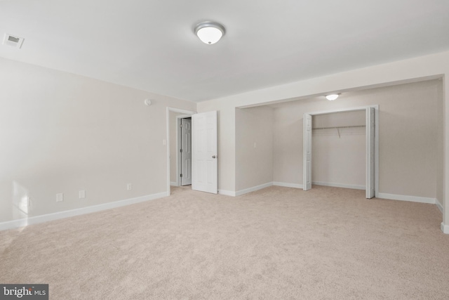 unfurnished bedroom featuring light carpet and a closet