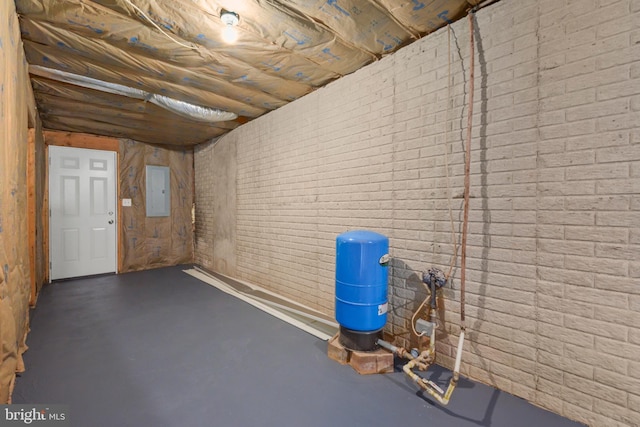 basement featuring electric panel and brick wall