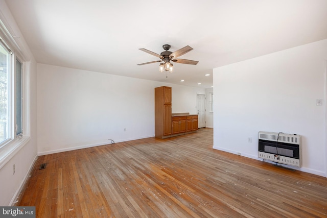 unfurnished living room with light wood-type flooring, heating unit, and ceiling fan