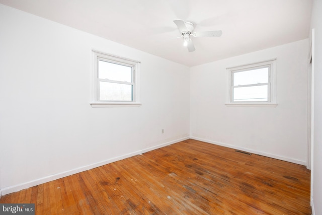 spare room featuring hardwood / wood-style floors, ceiling fan, and a wealth of natural light