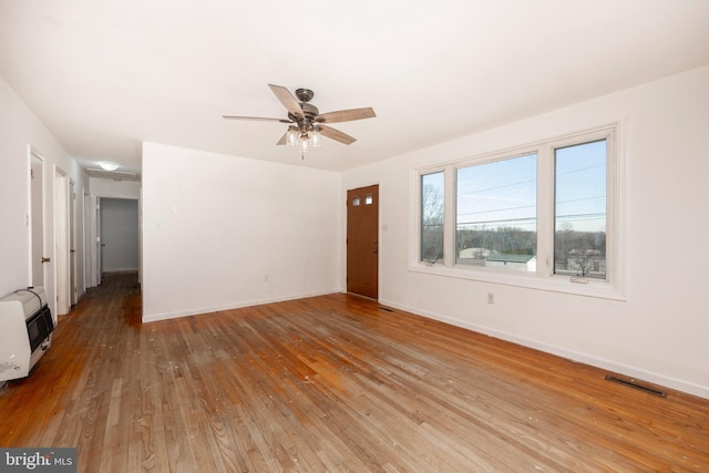 unfurnished room with ceiling fan, light wood-type flooring, and heating unit