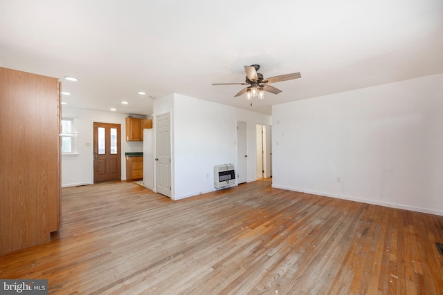 unfurnished living room with heating unit, ceiling fan, and light hardwood / wood-style floors