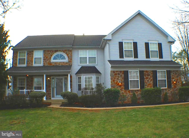 view of front of home featuring stone siding, a front lawn, and a porch