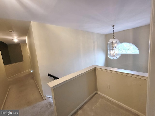 corridor with baseboards, light colored carpet, a notable chandelier, and an upstairs landing