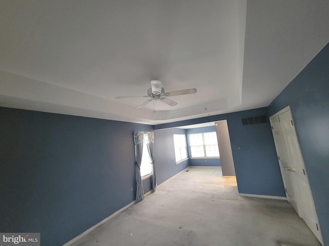 unfurnished room with a raised ceiling, visible vents, a ceiling fan, concrete floors, and baseboards