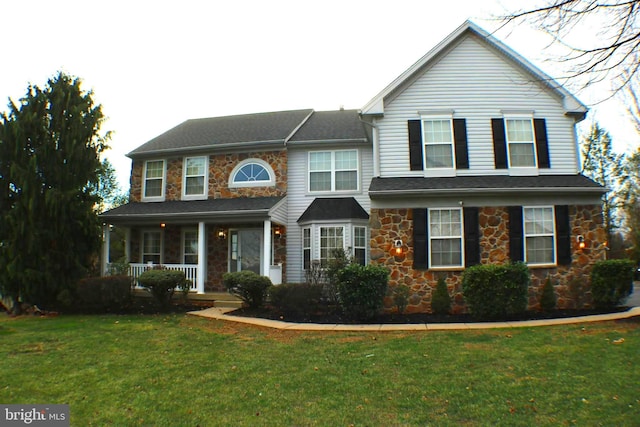 view of front of house with stone siding, a porch, and a front lawn