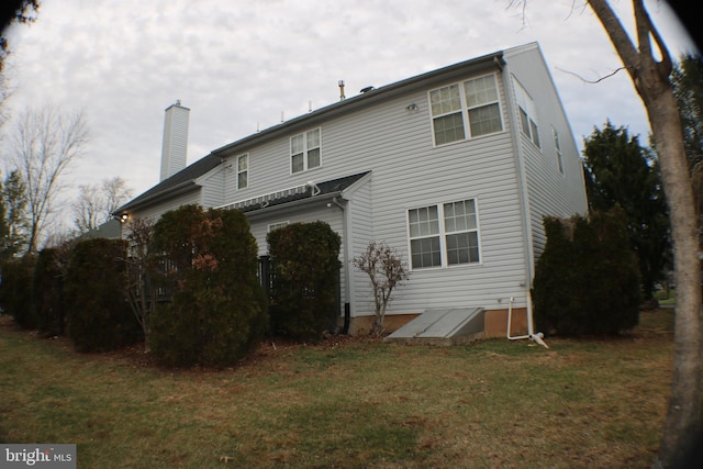 rear view of house featuring a yard and a chimney