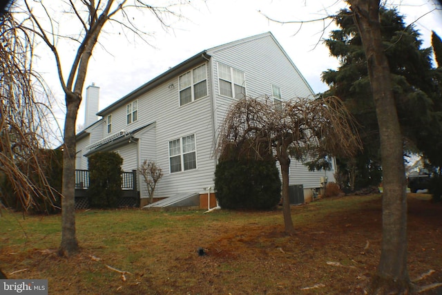 view of home's exterior featuring a chimney, cooling unit, and a lawn