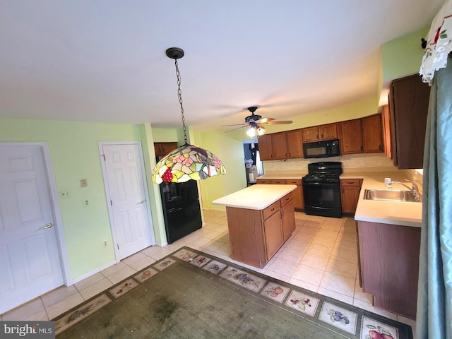 kitchen with decorative light fixtures, a center island, light countertops, black appliances, and a sink