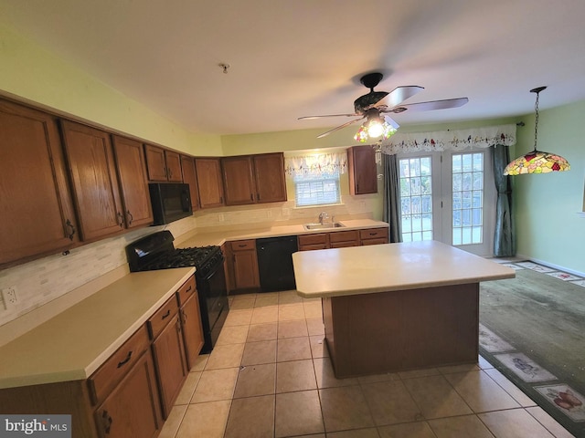 kitchen featuring a sink, light countertops, decorative backsplash, black appliances, and pendant lighting