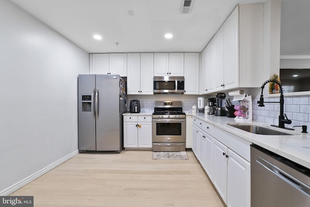 kitchen with white cabinets, light stone counters, sink, and stainless steel appliances