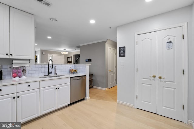 kitchen with light wood-type flooring, backsplash, stainless steel dishwasher, sink, and white cabinets