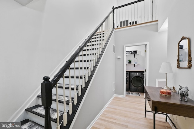 stairway with hardwood / wood-style floors, independent washer and dryer, and a towering ceiling