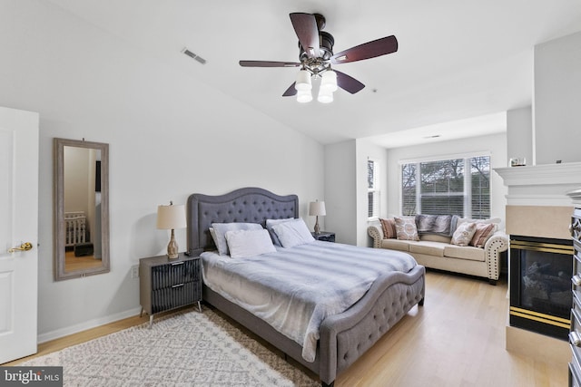 bedroom with ceiling fan, light wood-type flooring, and vaulted ceiling