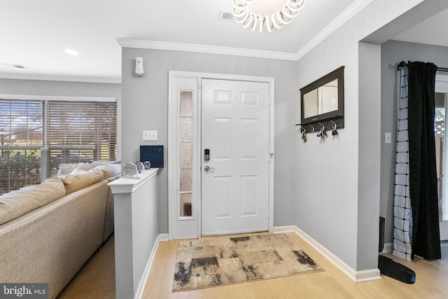 entrance foyer featuring wood-type flooring, ornamental molding, and a notable chandelier